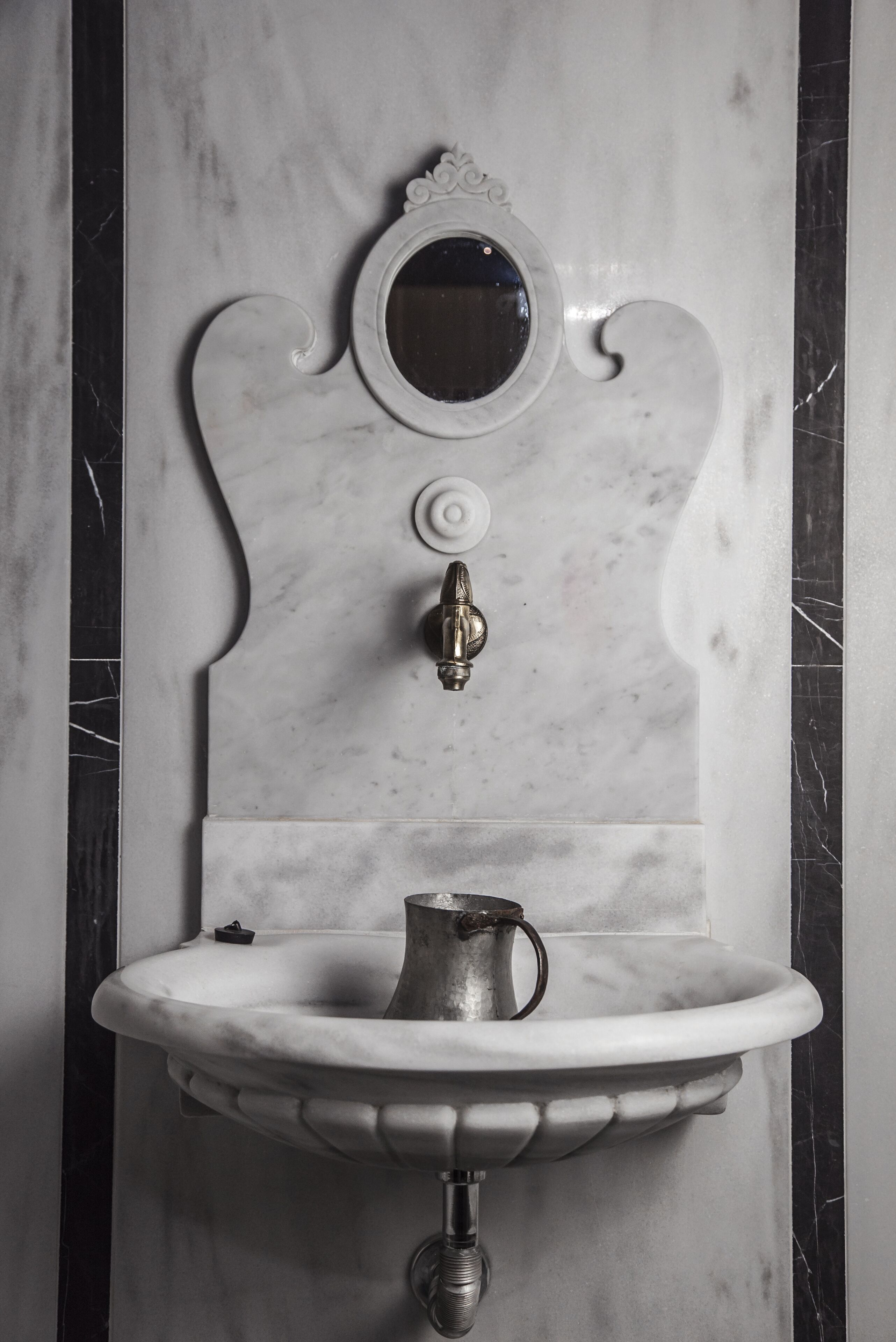 Un lavabo en marbre avec un seul robinet et un miroir au-dessus.