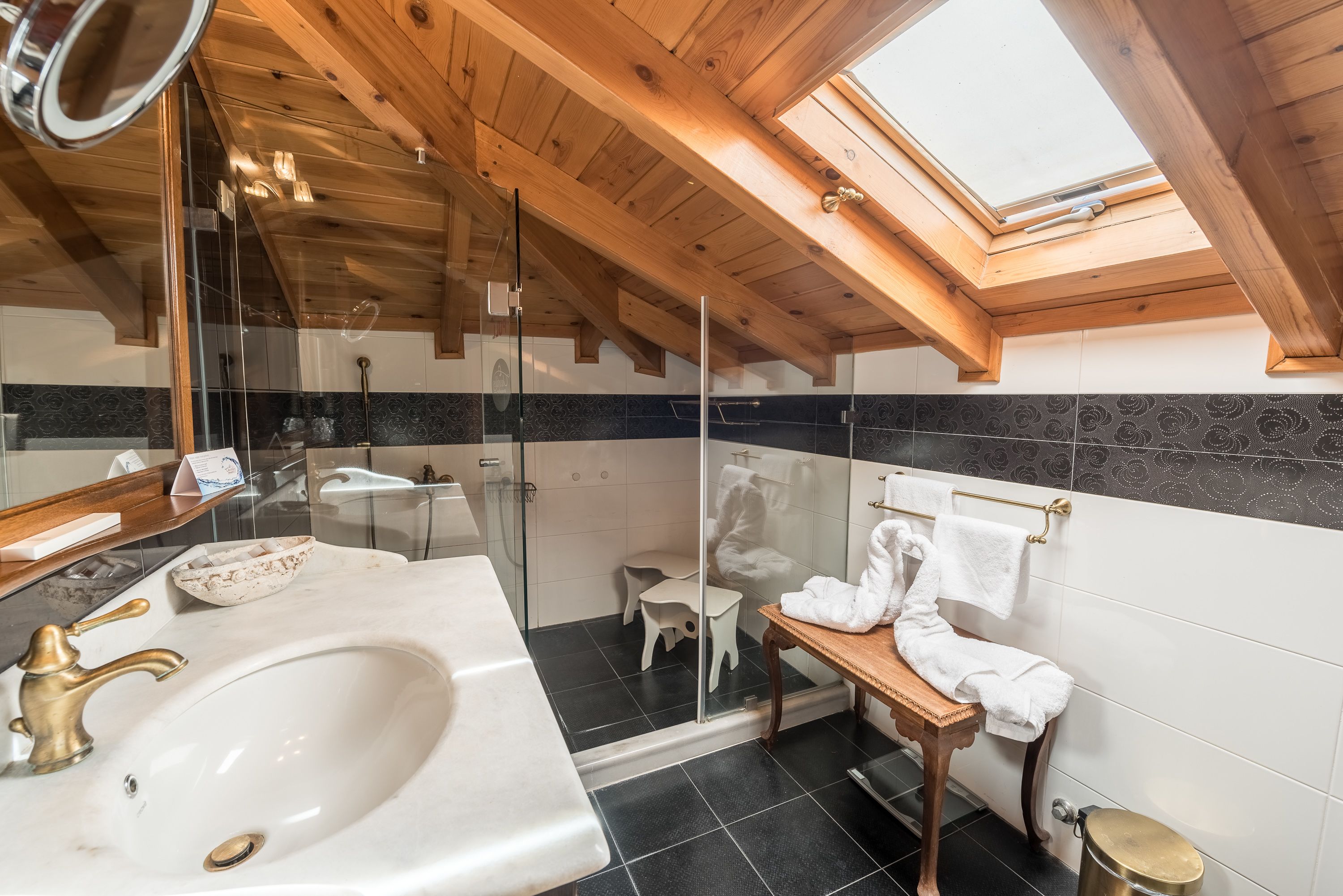 A modern bathroom with a skylight, a large sink, and a wooden vanity.