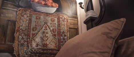 Una habitación con alfombra estampada, un tapiz decorativo y un cabecero de madera oscura.