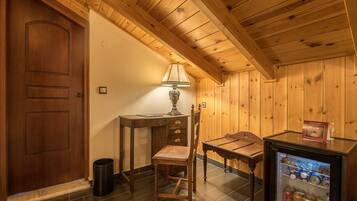 Una habitación con paneles de madera, una puerta, un escritorio, una silla, una lámpara y un refrigerador pequeño.