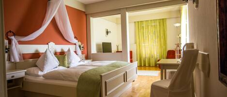 A hotel room with a bed, bedside table, chair, and a view of the dining area.