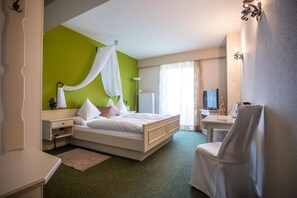 Een hotelkamer met een bed, een bureau, een stoel, een televisie en een raam met gordijnen.
