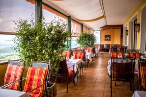 A restaurant with outdoor seating, tables with white tablecloths, and chairs with striped cushions. - Panoramahotel Steirerland (St Andra-Hoech)