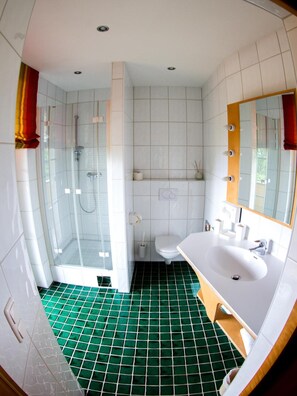Een badkamer met douche, toilet en wastafel.