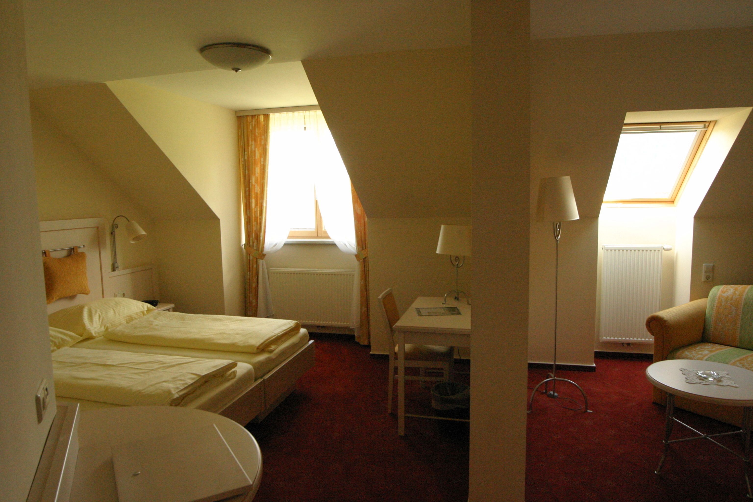 A hotel room with two beds, a desk, a chair, a small table, and a sofa.