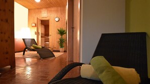 A wooden interior with a lounge chair, a potted plant, and a visible clock on the wall. - Hotel Stigenwirth (Krakauhintermuehlen)