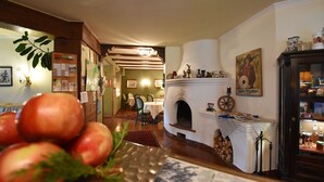 A dining area with a fireplace, a dining table with chairs, and a wall with framed pictures and a clock. - Hotel Stigenwirth (Krakauhintermuehlen)