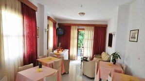 A hotel dining area with multiple tables, chairs, and a television.