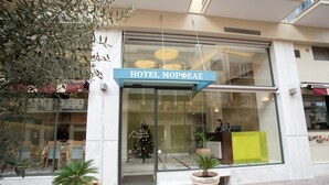 L’entrée d’un hôtel, avec une enseigne indiquant « HÔTEL MOPHÆA ».