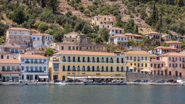 A coastal town with buildings along the waterfront, including a yellow building with multiple windows and balconies.
