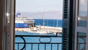 A view from a balcony with a metal railing overlooking a harbor with boats and a large ship docked.