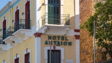 Hotel anomenat "HOTEL AKTION" amb un balcó, paret de pedra i un cartell de "NEOPTIC".