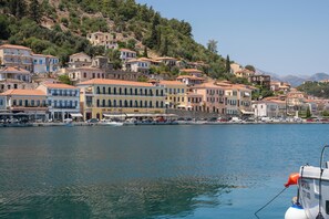 Une ville côtière avec des bâtiments le long du front de mer, un ciel dégagé et un bateau amarré au quai.