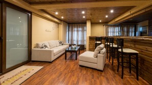 Un salon chaleureux avec un canapé, un fauteuil et des chaises de salle à manger, un plancher en bois et un plafond en bois.
