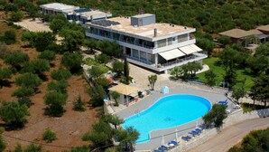 Una casa moderna con piscina, rodeada de árboles y un paisaje montañoso.