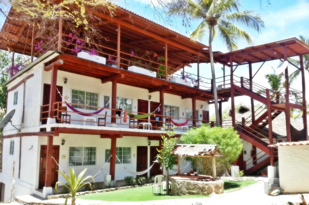 Un edificio de dos pisos con balcón, escalera y un pequeño espacio para sentarse al aire libre.
