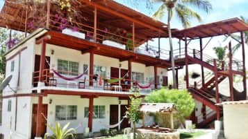 A two-story building with a balcony, a staircase, and a small outdoor seating area.