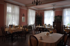 A dining area with tables set for meals, chairs, and a chandelier.