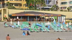 Un bar en la playa con terraza y sombrillas.