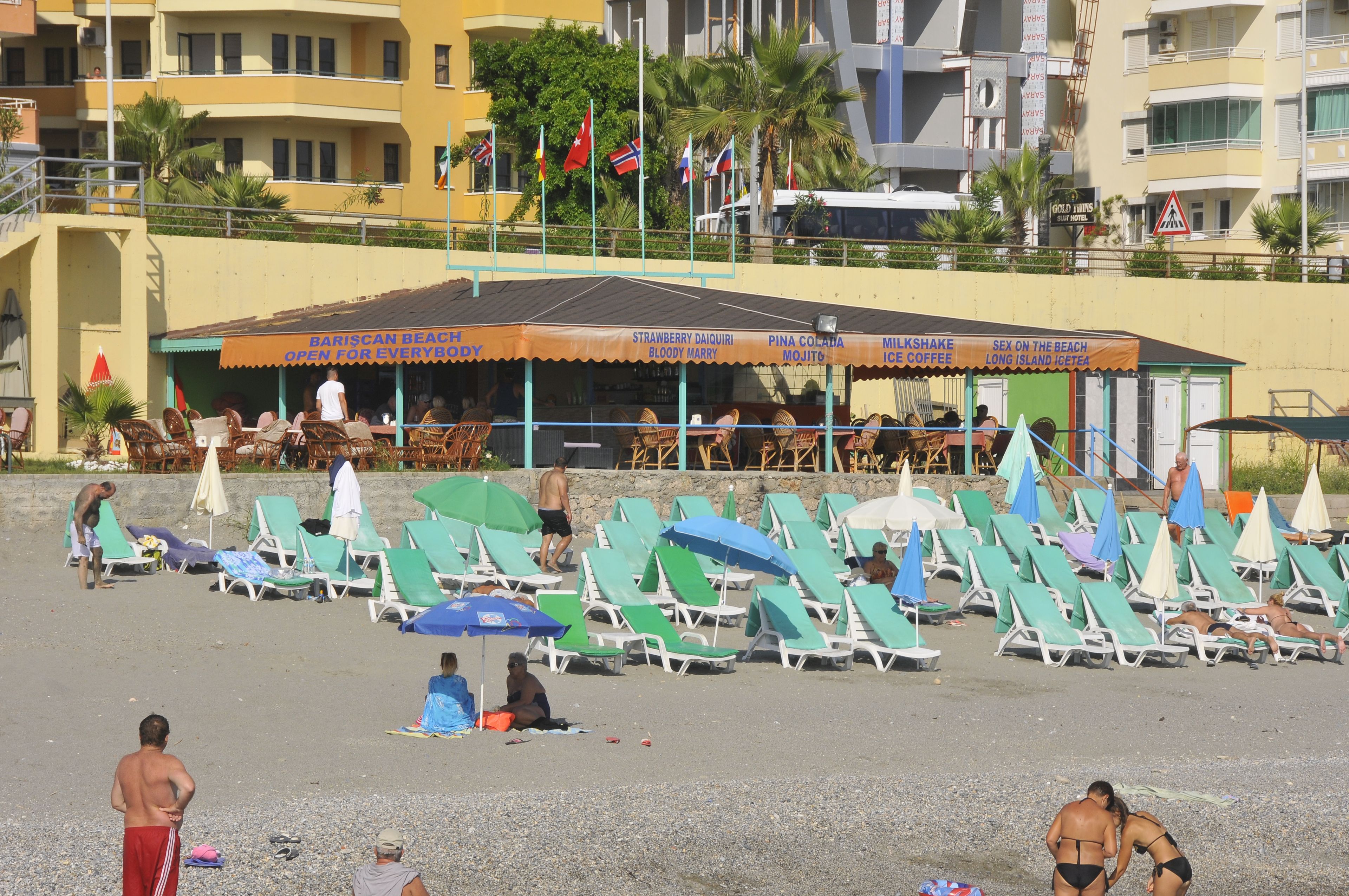 Un bar en la playa con terraza y sombrillas.