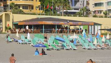 Un bar en la playa con terraza y sombrillas.
