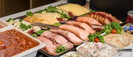 Un bufé con diversos alimentos, como embutidos, quesos y ensaladas.