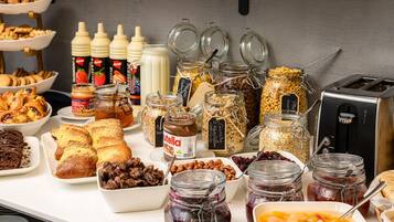 Un buffet proposant une variété d’aliments, notamment des pâtisseries, des fruits secs et des pots de confitures et de pâtes à tartiner.