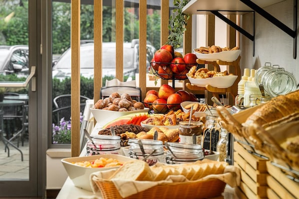 Un buffet de petit-déjeuner proposant une variété d’aliments, avec vue sur les voitures garées à l’extérieur.