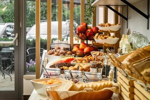 A breakfast buffet with various food items and a view of parked cars outside.