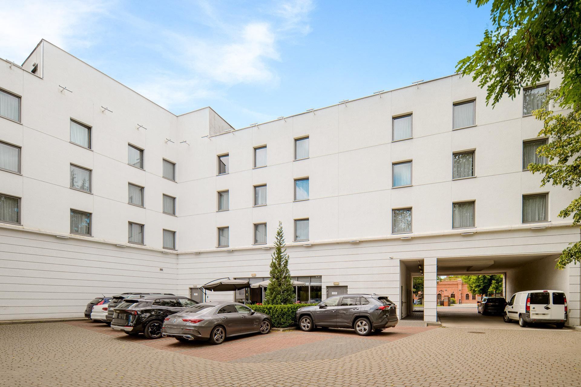 A multi-story building with a parking area in front.