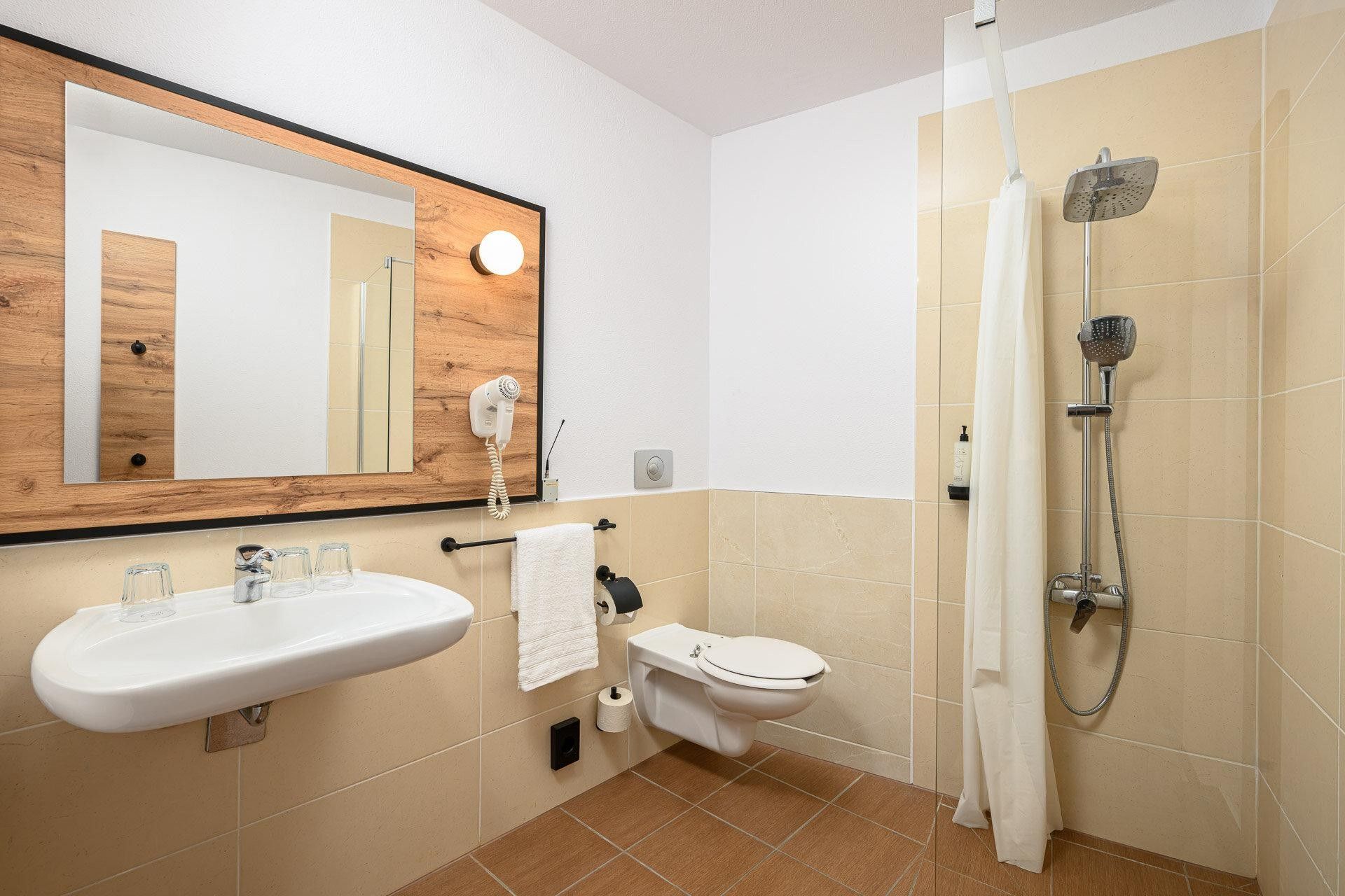 Un baño con lavamanos, inodoro, espejo y ducha.