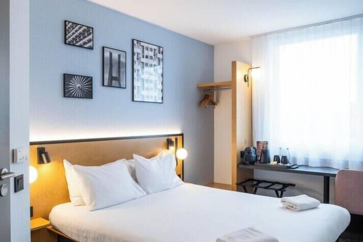 Una habitación de hotel con cama, mesitas de noche, escritorio y silla.