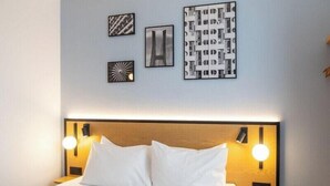 A hotel room with a bed, two bedside lamps, and three wall art pieces. - B&B Hotel Torun (Torun)