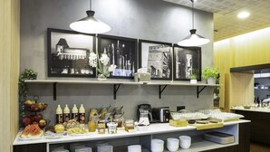A breakfast bar with a variety of food items and condiments, including fruits, pastries, and beverages. There are also framed pictures on the wall above the bar. - B&B Hotel Torun (Torun)