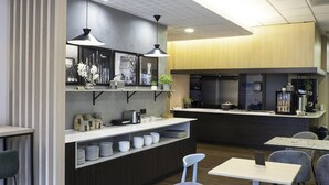 A modern kitchen with a central island, pendant lighting, and a seating area with tables and chairs. - B&B Hotel Torun (Torun)