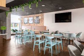 A modern interior with a brick wall, multiple seating areas, and hanging plants. - B&B Hotel Torun (Torun)