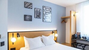A hotel room with a bed, bedside lamps, a small table with a coffee maker, and wall art. - B&B Hotel Torun (Torun)