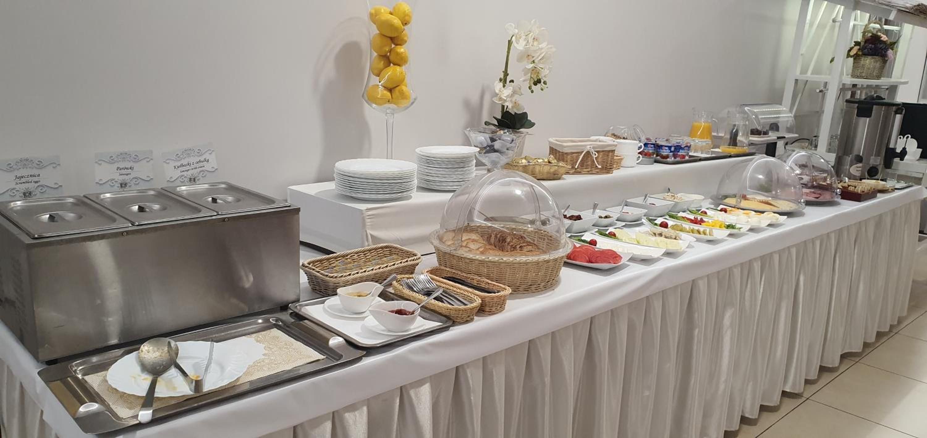 A buffet setup with various food items, serving utensils, and decorative elements like flowers and baskets.