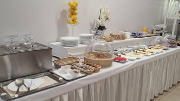 A buffet setup with various food items, serving utensils, and decorative elements like flowers and baskets.