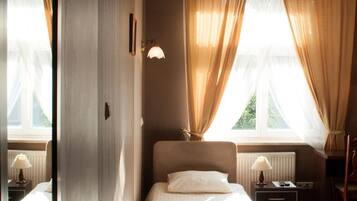 A hotel room with a bed, bedside tables, a desk, a chair, and a television.