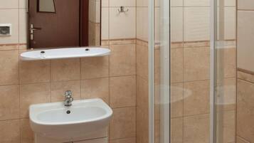 A bathroom with a sink, mirror, and shower.