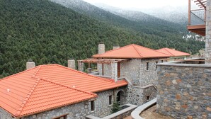 A stone building with red-tiled roofs and a mountainous backdrop.