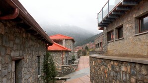 A stone building with a red-tiled roof and a stone pathway leading to a mountain view.
