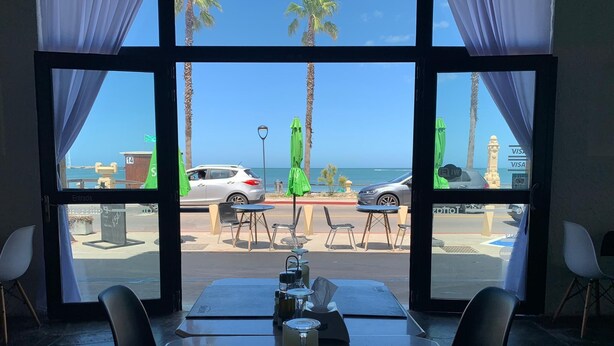 Un restaurante con vistas a la playa y al océano, que ofrece mesas al aire libre y una mesa preparada para dos.