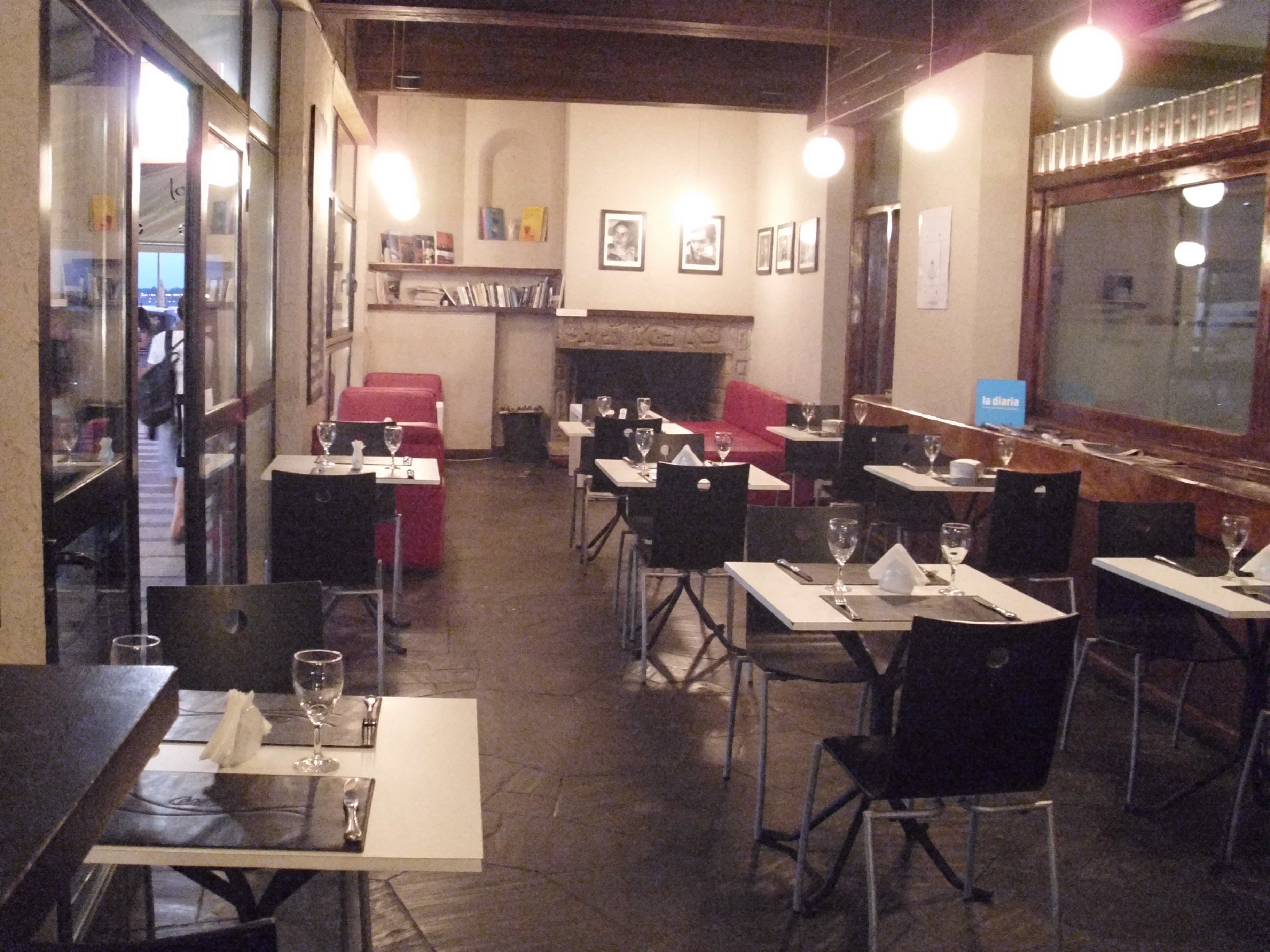 A restaurant with tables and chairs, a fireplace, and framed pictures on the wall.