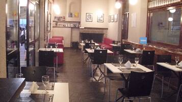 A restaurant with tables and chairs, a fireplace, and framed pictures on the wall.
