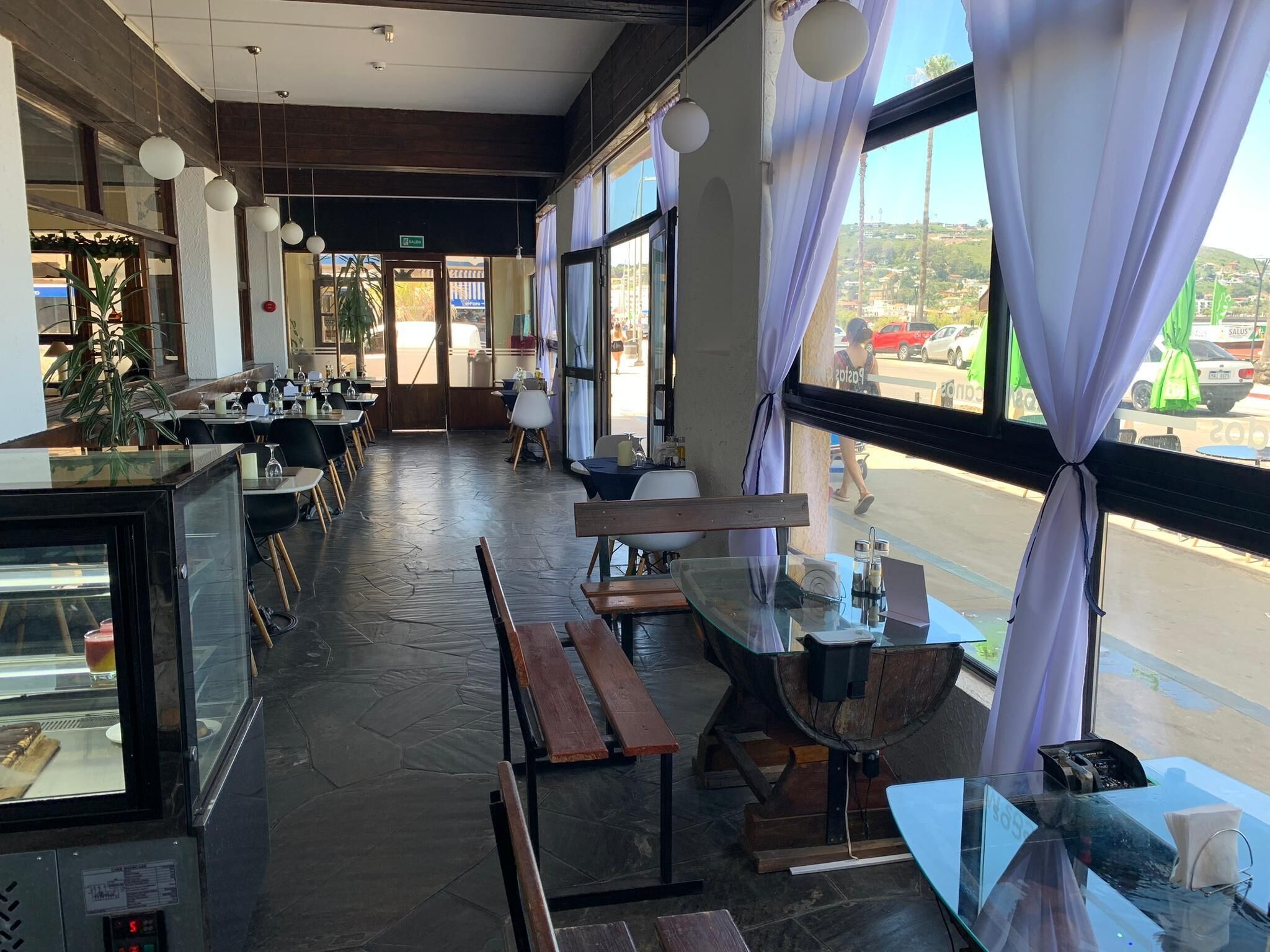 A restaurant with a long counter, wooden benches, and a glass display case.
