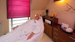 A room with a bed, a wooden cabinet with toiletries, and a window with a red blind. - Geovita Krynica Zdroj (Krynica-Zdroj)