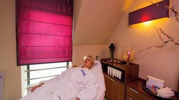 A room with a bed, a wooden cabinet with toiletries, and a window with a red blind.