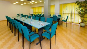 A conference room with a long table, teal chairs, and yellow curtains. - Geovita Krynica Zdroj (Krynica-Zdroj)